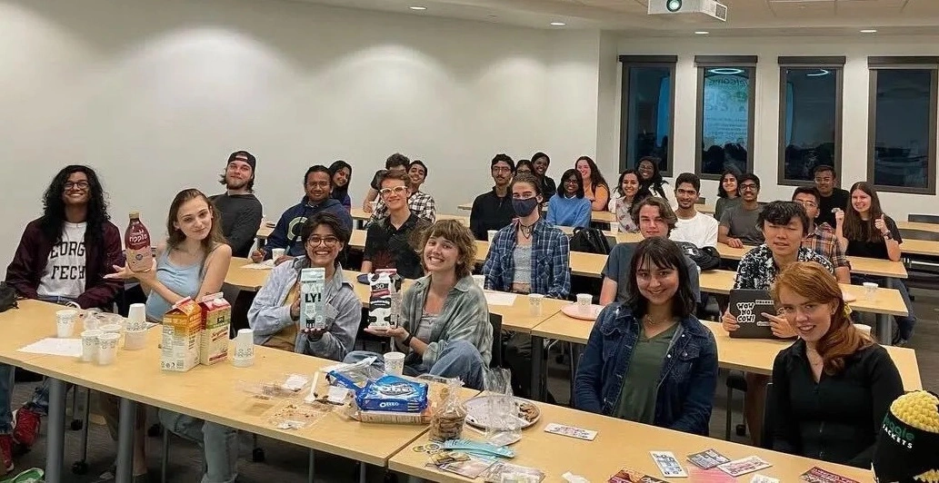 A group of GT students in a classroom with vegan milk and cookies on a table